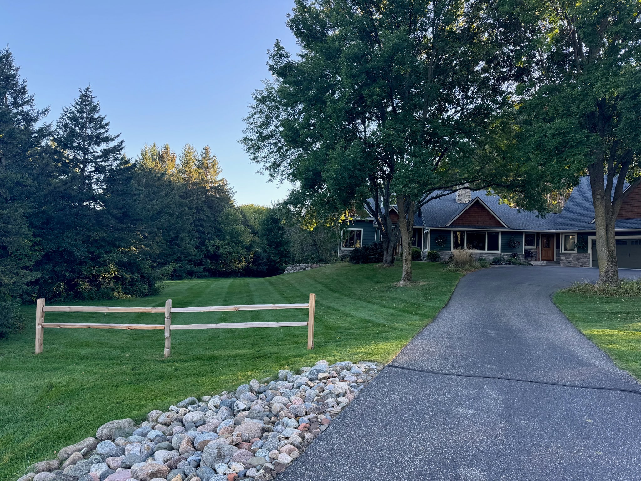 Freshly mowed lawn beside a paved driveway and landscaped home.